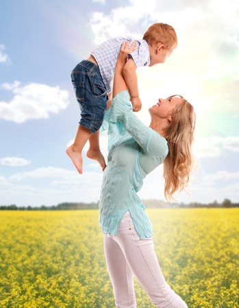 Portrait of happy mother with joyful son over sping flower fieldの写真素材