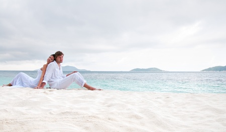 Young couple sitting on the beach near the seasideの写真素材