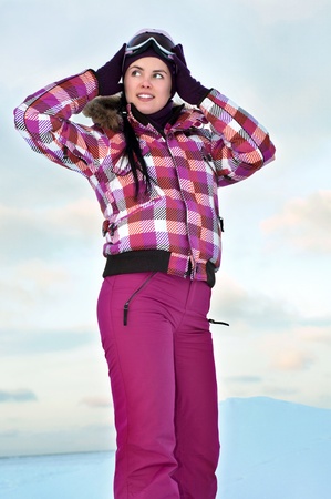 Beautiful young woman wearing skiing suit posing outdoors in winterの写真素材