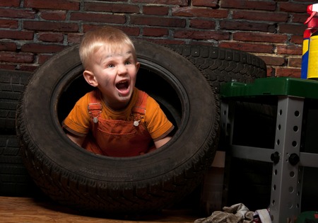 Cute and funny little mechanic with a tire の写真素材