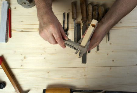 Cropped image of senior carpenter measuring wood