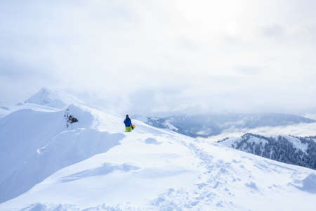 freeride backcountry snowboarder on the trail on mountain ridge covered with snow powderの写真素材