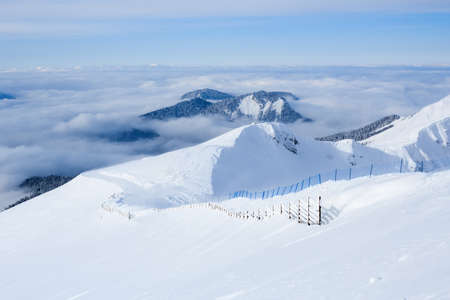 wooden fence and ski trail in the caucasus mountains covered with snowの写真素材