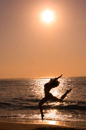 Female jumping at beach on sunriseの写真素材