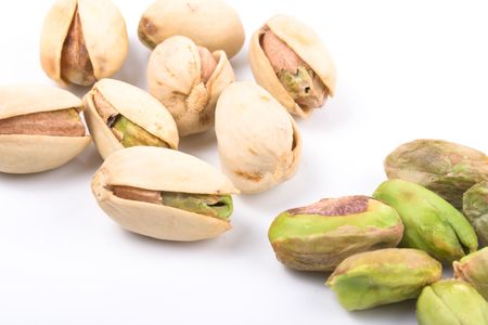 Several pistachio nuts naked and in shell close up isolated on whiteの写真素材