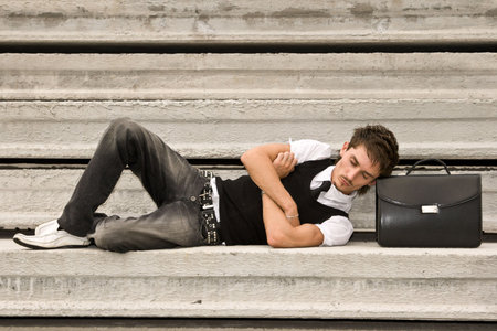 Young tired man sleeping with head resting on a brifcaseの写真素材