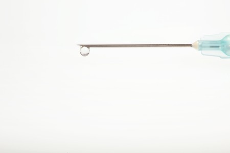 Drop on syringe needle macro. Small depth of field. Lots of copyspace.の写真素材