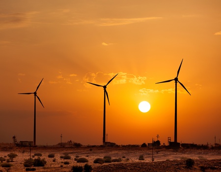 Green renewable energy concept - wind generator turbines sihouettes on sunsetの写真素材