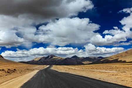 Travel forward concept background - road on plains in Himalayas with mountains and dramatic clouds. Manali-Leh road, Ladakh, Jammu and Kashmir, Indiaの写真素材