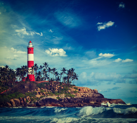 Vintage retro hipster style travel image of old lighthouse and waves of  sea. Kovalam (Vizhinjam) Kerala, Indiaの写真素材