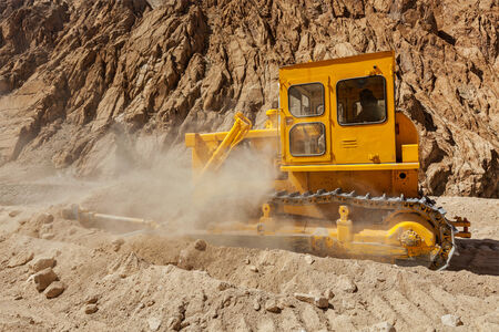 Bulldozer doing road construction in Himalayas. Ladakh, Jammu and Kashmir, Indiaの写真素材
