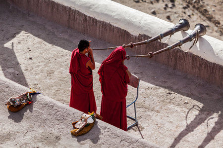 THIKSEY, INDIA - SEPTEMBER 4, 2011: Two Tibetan Buddhist monks blowing Tibetan horn (dungche) during morning pooja, Thiksey gompa, Ladakh, Indiaのeditorial素材