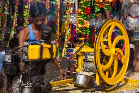 PUSHKAR, INDIA - NOVEMBER 20, 2012: Street vendor makes sugarcane juice by crushing peeled sugar...