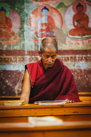 THIKSEY, INDIA - SEPTEMBER 4, 2011: Old Tibetan Buddhist monk during prayer in Thiksey gompa (Buddhist monastery)  of the Yellow Hat (Gelugpa) sect - the largest gompa in central Ladakhのeditorial素材