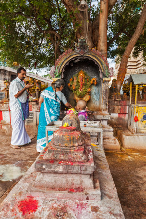 MADURAI, INDIA - FEBRUARY 16, 2013: Indian pilgrim family worshipping Hindu god Ganesh in famous Meenakshi Amman Temple - historic Hindu temple located in temple city Maduraiのeditorial素材