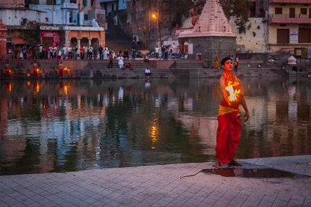 UJJAIN, INDIA - APRIL 23, 2011: Brahmin performing Aarti pooja ceremony on bank of holy river Kshipra. Aarti is Hindu religious ritual of worship, part of puja when light is offered to one or more deitiesのeditorial素材
