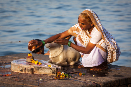 MAHESHWAR, INDIA - APRIL 26: Indian woman performs morning pooja on sacred river Narmada ghats on April 26, 2011 in Maheshwar, Madhya Pradesh, India. To Hindus Narmada is one of 5 holy rivers of Indiaのeditorial素材