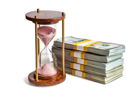 Time is money loan concept background - hourglass and stack of new 100 US dollars 2013 edition...