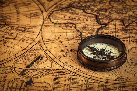 Travel geography navigation concept background - old vintage retro compass on ancient world mapの写真素材