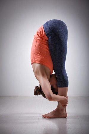 Beautiful sporty fit yogini woman practices yoga asana Uttanasana - standing forward bend poseの写真素材