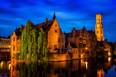 Famous view of Bruges - Rozenhoedkaai with Belfry and old houses along canal with tree in the night. Brugge, Belgiumの写真素材