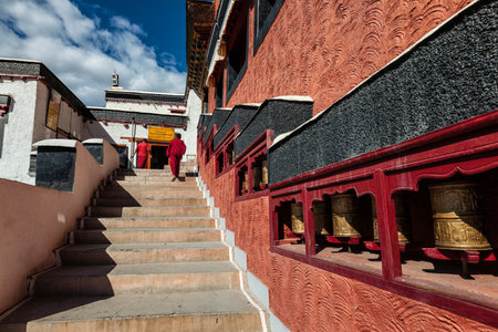 THIKSEY, INDIA - SEPTEMBER 13, 2012: Young Buddhist monks walking on stairs along prayer wheels in Thiksey gompa Tibetan Buddhist monastery, Ladakh, Indiaのeditorial素材