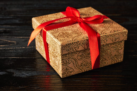 Gift birthday Christmas present concept - gift box with red ribbon on dark wooden backgroundの写真素材