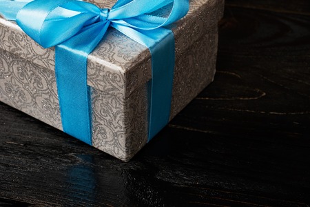Gift birthday Christmas present concept - silver gift box with blue ribbon on dark wooden backgroundの写真素材