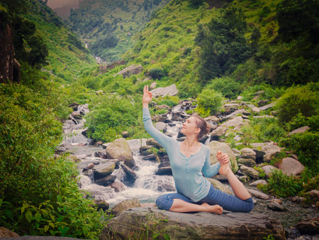 Yoga outdoors - young sporty fit woman doing stretching yoga asana Eka pada rajakapotasana -...