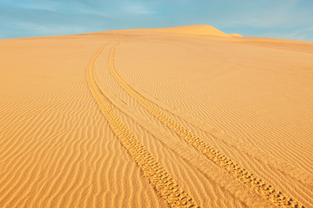 All-terrain vehicle ATV tracks in white sand dunes on sunrise,の写真素材
