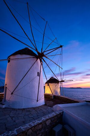 Scenic view of famous Mykonos Chora town windmills. Traditional greek windmills on Mykonos island illuminated in the evening, Cyclades, Greece. Walking with steadycam.の写真素材