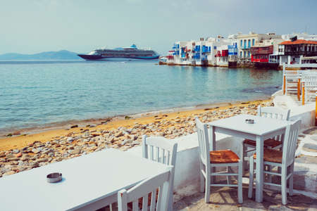 Cafe table and cruise liner in Aegean sea. Chora, Mykonos island, Greeceの写真素材