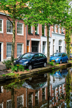 Cars on canal embankment in street of Delft. Delft, Netherlandsの写真素材
