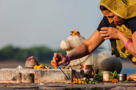 Indian woman performs morning pooja on holy river Narmada ghats