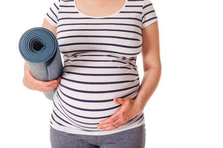 Pregnant woman standing with yoga mat