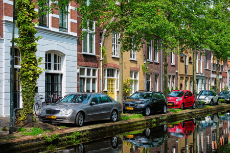 Cars on canal embankment in street of Delft. Delft, Netherlandsのeditorial素材