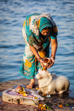 Indian woman performs morning pooja on holy river Narmada ghatsのeditorial素材