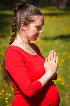 Pregnant woman doing asana Tadasana Mountain pose outdoorsの写真素材