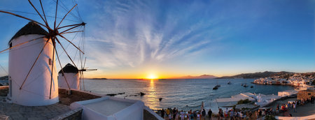 Traditional greek windmills on Mykonos island on sunset with dramatic sky and Little Venice quarter with tourist crowdのeditorial素材