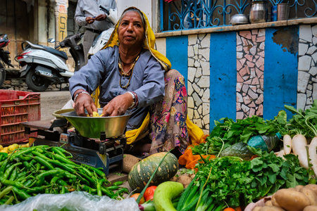 Pushkar, India - November 7, 2019: Woman street vegetable vendor selling vegetables in the street of Pushkar, Rajasthan, Indiaのeditorial素材