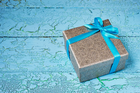 Gift birthday Christmas present concept - silver gift box with blue ribbon on blue painted wooden backgroundの写真素材