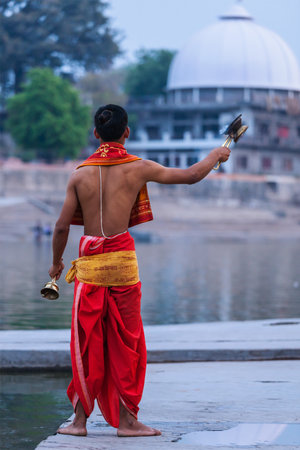 UJJAIN, INDIA - APRIL 23, 2011: Brahmin performs Aarti pooja ceremony on holy river Kshipra bank. Aarti is Hindu religious ritual of worship part of puja when light is offered to one or more deitiesのeditorial素材