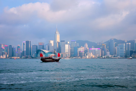 HONG KONG, CHINA - APRIL 28, 2018: Hong Kong skyline cityscape downtown skyscrapers over Victoria Harbour in the evening on sunset with tourist junk boat ferries . Hong Kong, Chinaのeditorial素材