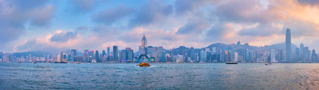 HONG KONG, CHINA - APRIL 28, 2018: Hong Kong skyline cityscape downtown skyscrapers over Victoria Harbour in the evening on sunset with junk tourist boat ferries . Hong Kong, Chinaのeditorial素材