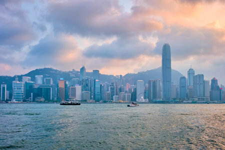HONG KONG, CHINA - APRIL 28, 2018: Hong Kong skyline cityscape downtown skyscrapers over Victoria Harbour in the evening on sunset with junk tourist boat ferries . Hong Kong, Chinaのeditorial素材