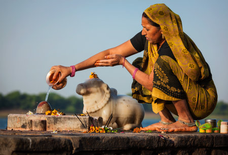 MAHESHWAR, INDIA - APRIL 26: Indian woman performs morning pooja on sacred river Narmada ghats on April 26, 2011 in Maheshwar, Madhya Pradesh, India. To Hindus Narmada is one of 5 holy rivers of Indiaのeditorial素材