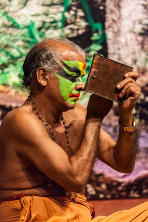 KOCHI, INDIA - FEBRUARY 24, 2013: Unidentified Kathakali exponent preparing for performance by applying face make-up. Kathakali is the classical dance form of Keralaのeditorial素材