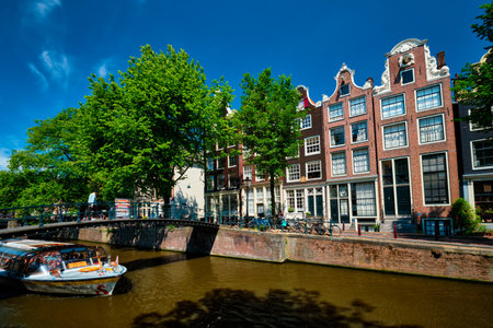AMSTERDAM, NETHERLANDS - MAY 21: Amsterdam canal with tourist boat passing under bridge and old houses. Amsterda, Netherlandsのeditorial素材
