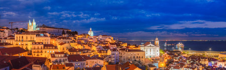 Panorama of Lisbon famous view from Miradouro de Santa Luzia tourist viewpoint over Alfama old city district at night. Lisbon, Portugal.の写真素材