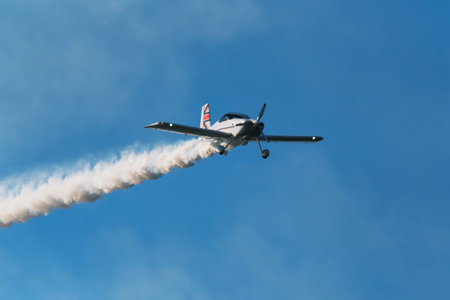 Stunt aerobatic plane performing stunts in blue sky with smoke trail. Concept of speed, difficulty,...